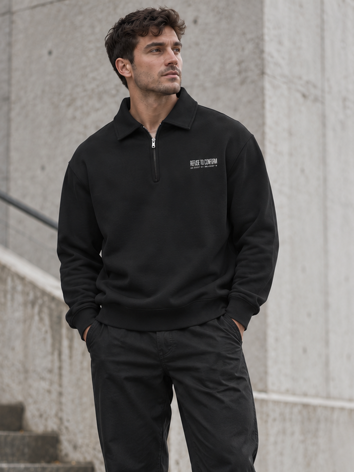 Model wearing black Refuse to Conform quarter-zip sweatshirt with small white chest logo in an urban setting