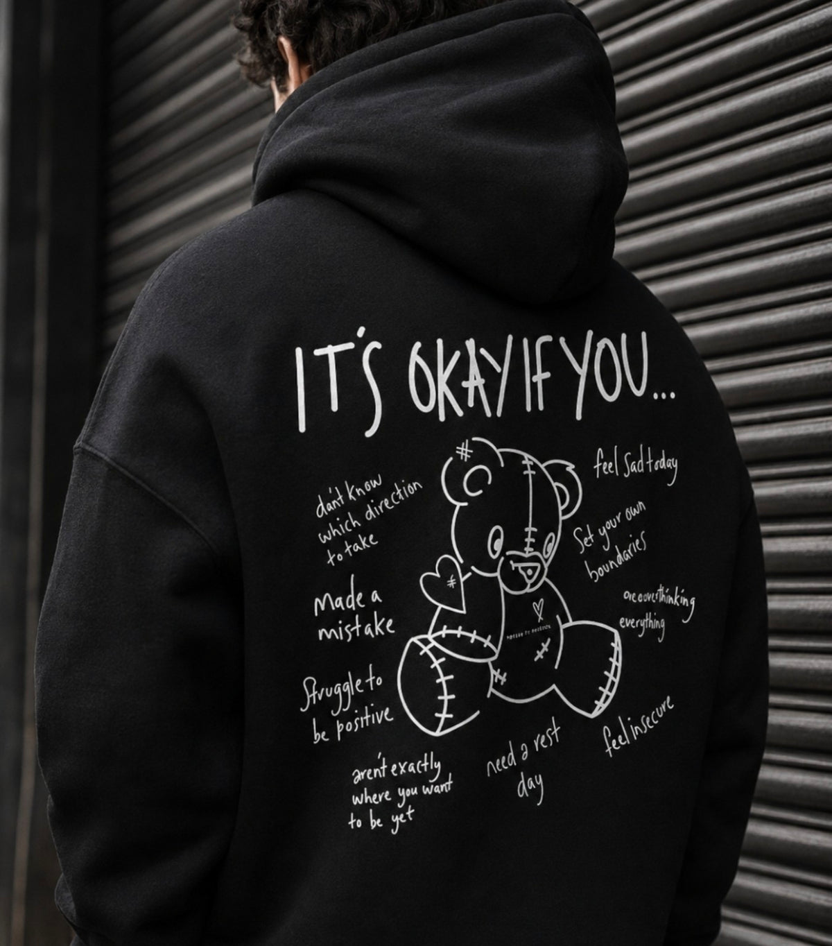 Model wearing a black Refuse to Conform hoodie in an urban setting